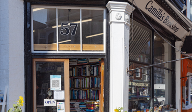 Outside front of Camillas Bookshop with second hand books piled high on shelves visible through the door way and windows